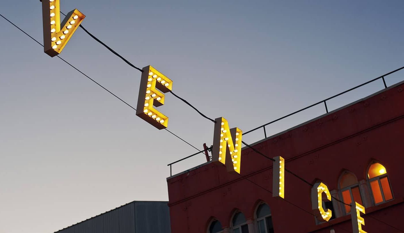 Venice sign glowing above a red brick building at dusk